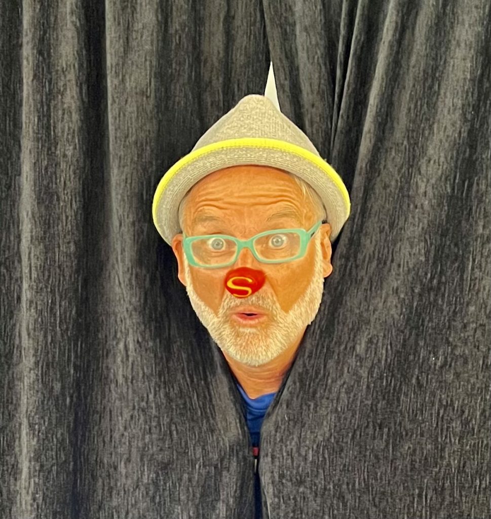 tete de clown magicien à travers son rideau de scene